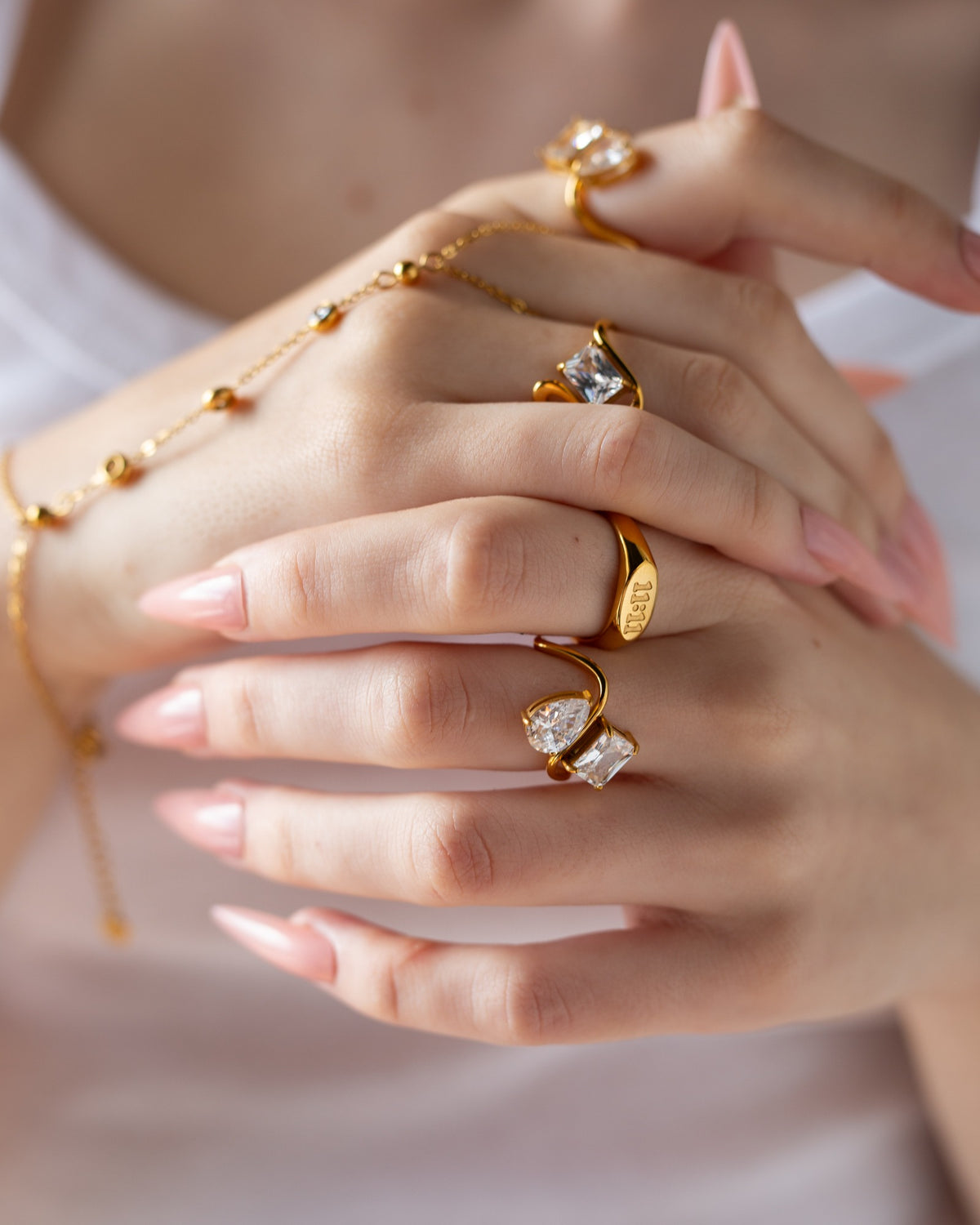 11:11 engraved ring styled with layered gold jewelry and pale pink nails.