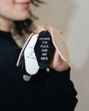 Hand holding assorted motel-style keychains including the Sorry I'm Late, I Didn't Want to Come Keychain