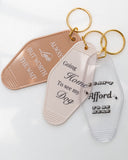 Hand holding assorted motel-style keychains including the Going Home to See My Dog Keychain