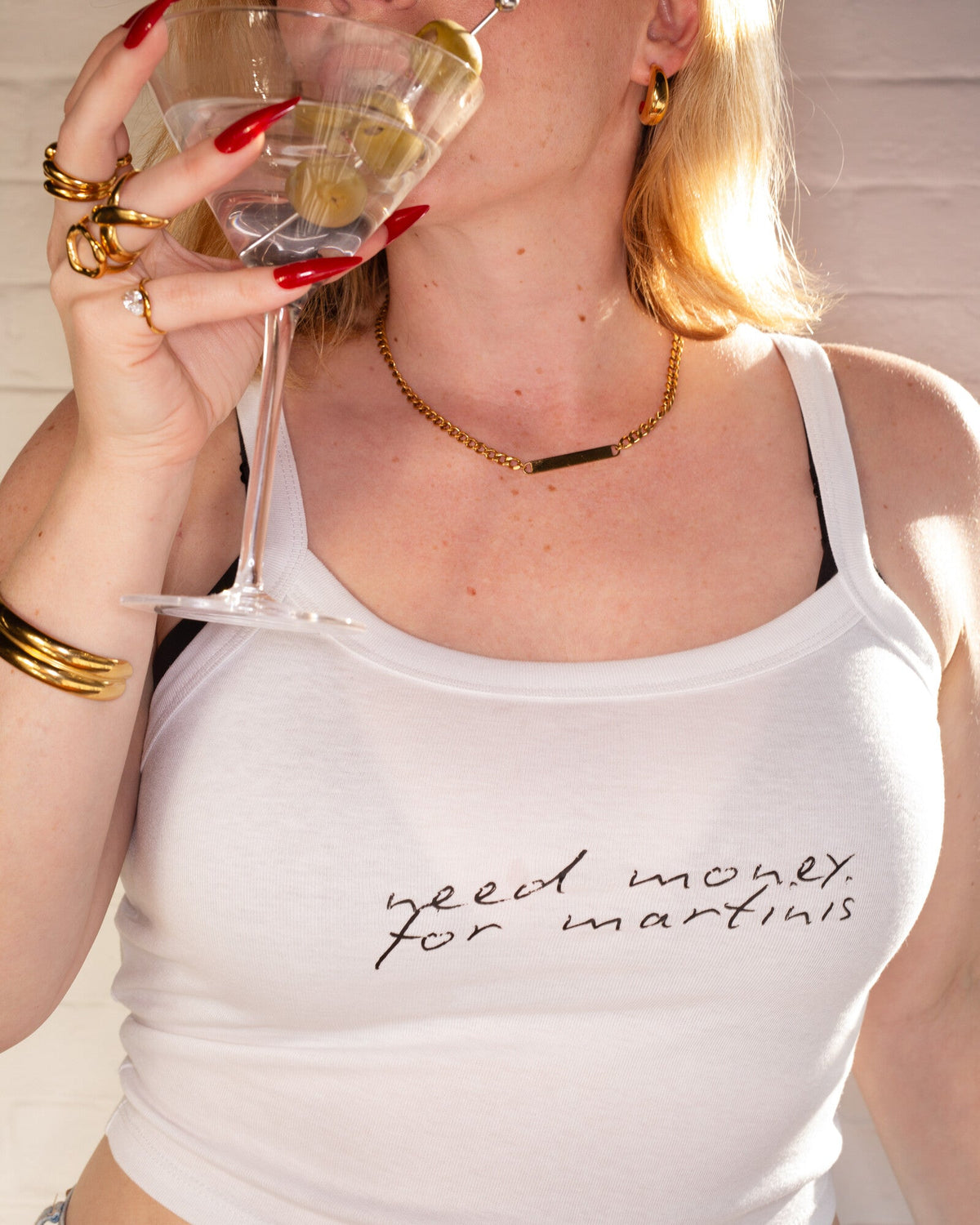 Model wearing the white Need Money for Martinis cami tank while holding a martini glass.