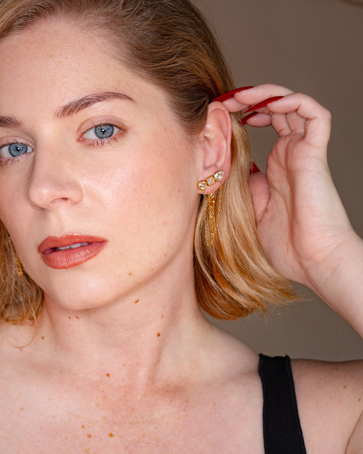 Ariadne chain tassel earring worn at the ear in a close-up portrait.