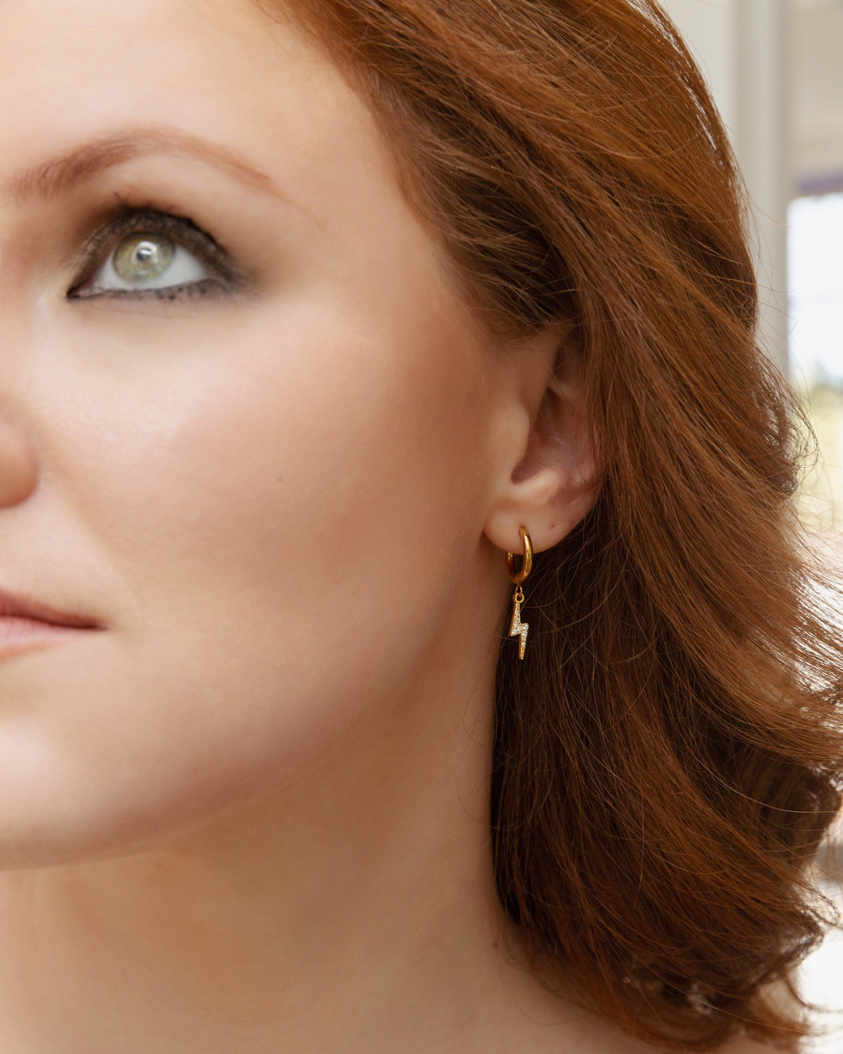 Astrape lightning bolt huggie earring worn in a polished side portrait.
