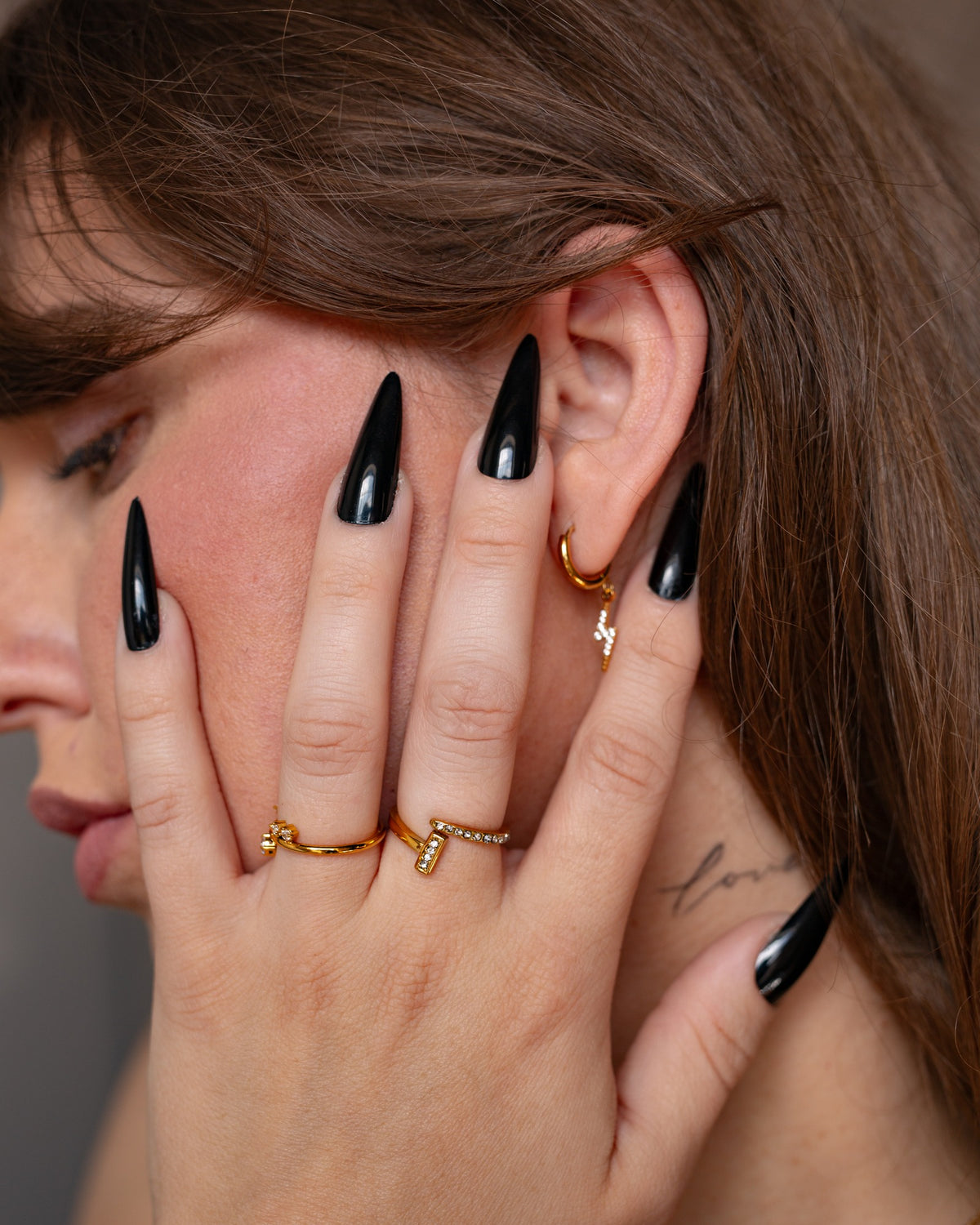 Astrape lightning bolt earring shown with black nails and stacked gold rings.