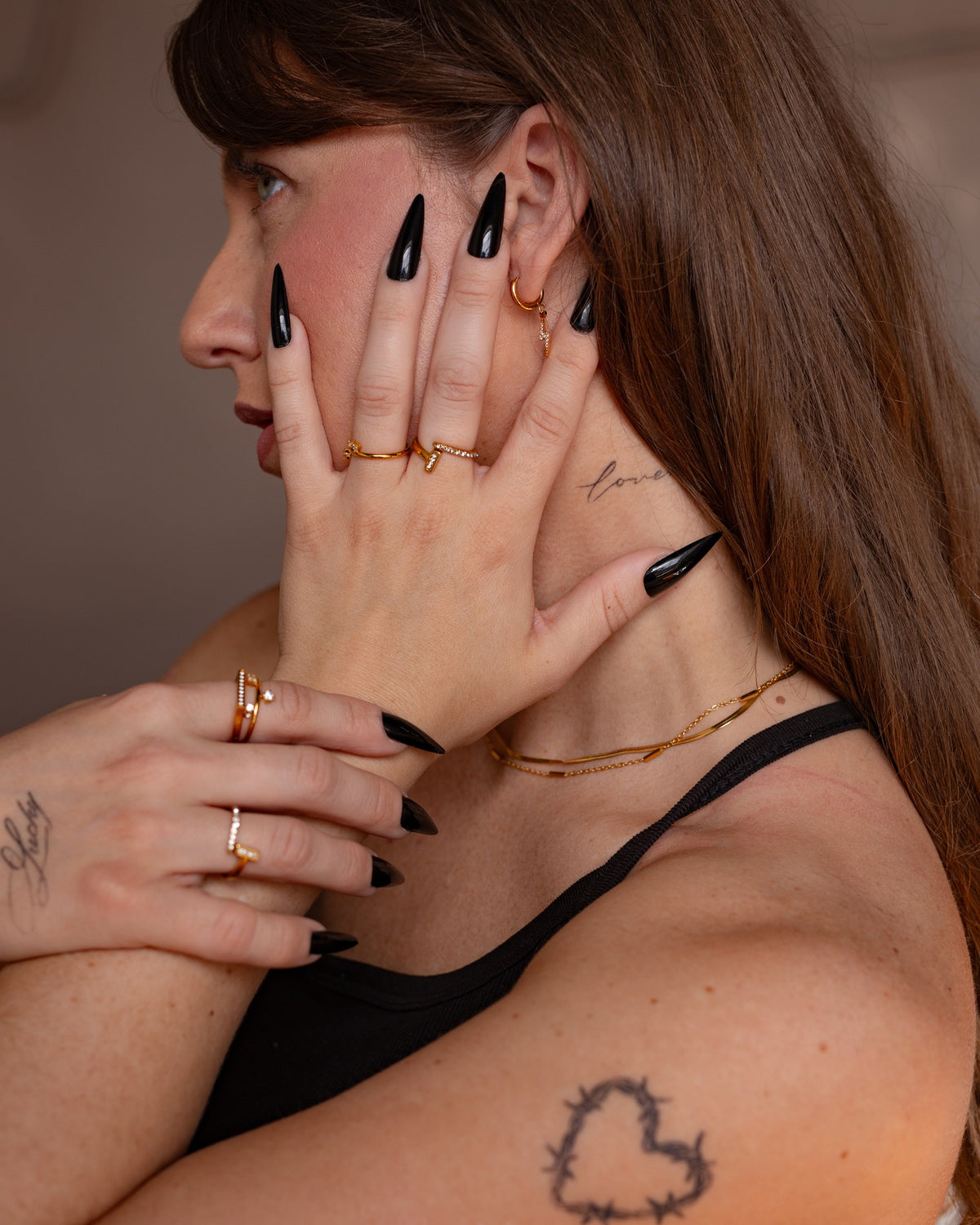 Astrape lightning bolt earring worn with black nails and layered gold jewelry.