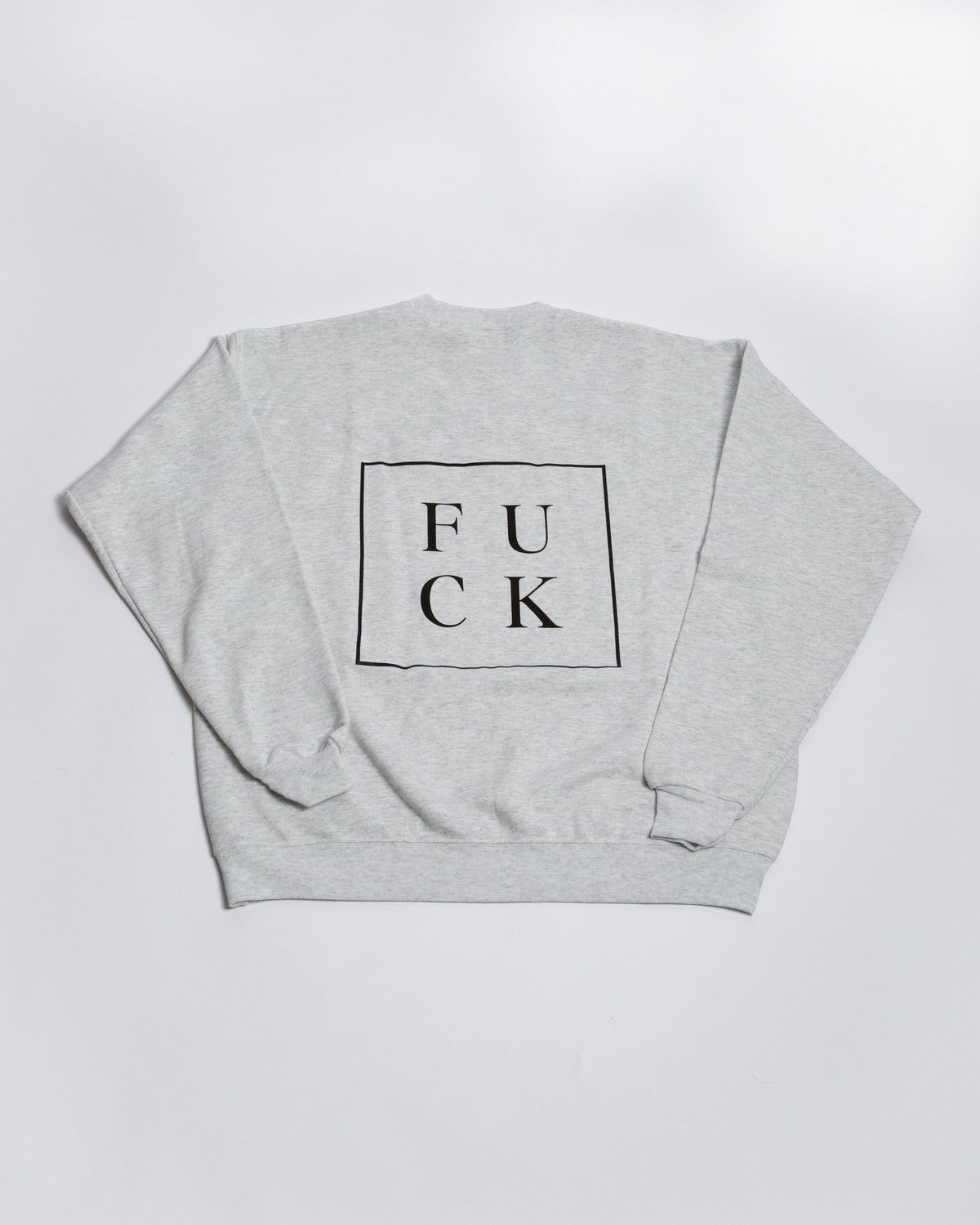 Detail view of the boxed F U C K graphic on a heather-gray crewneck.