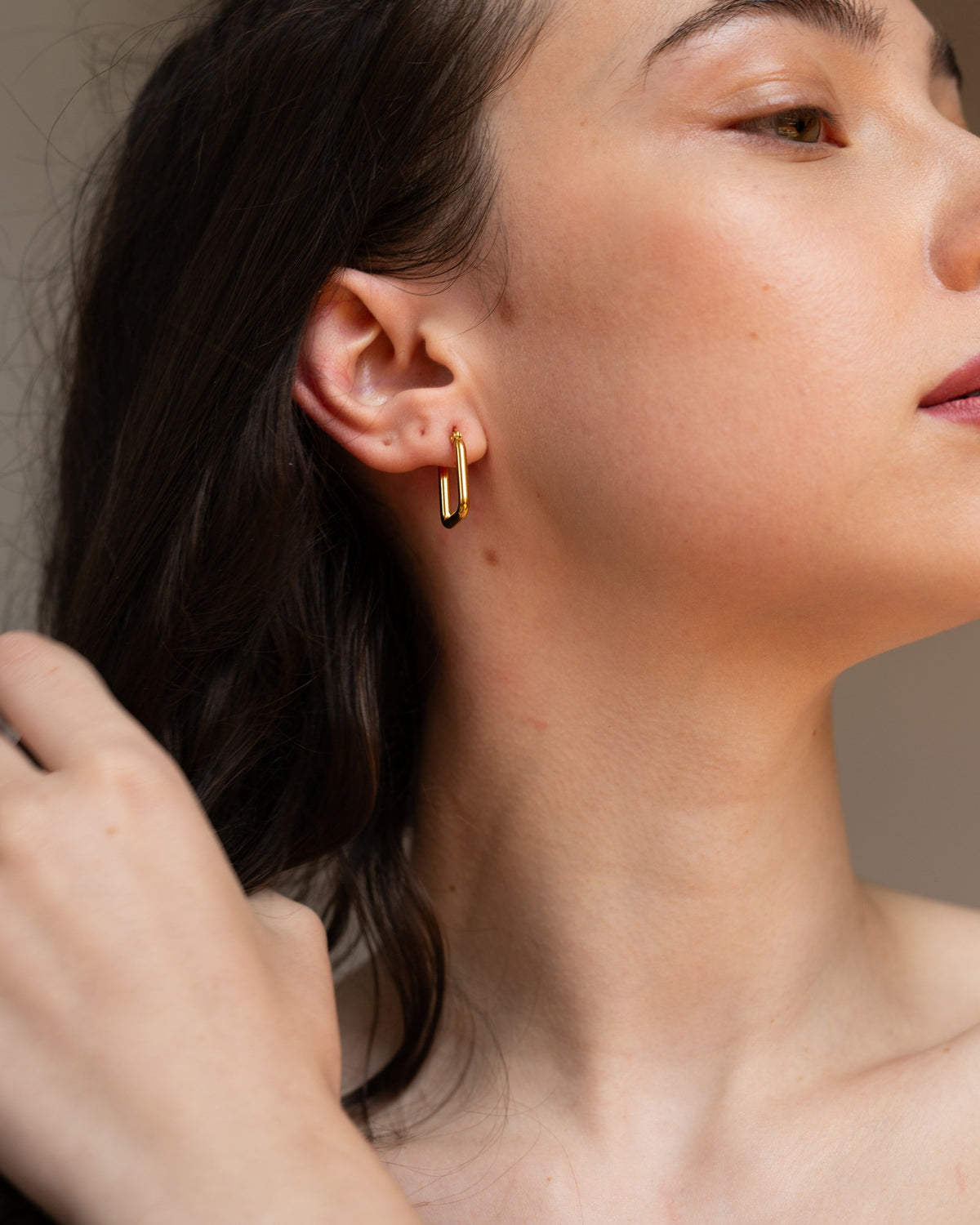 Circe rectangular gold hoop worn in a polished close-up portrait.