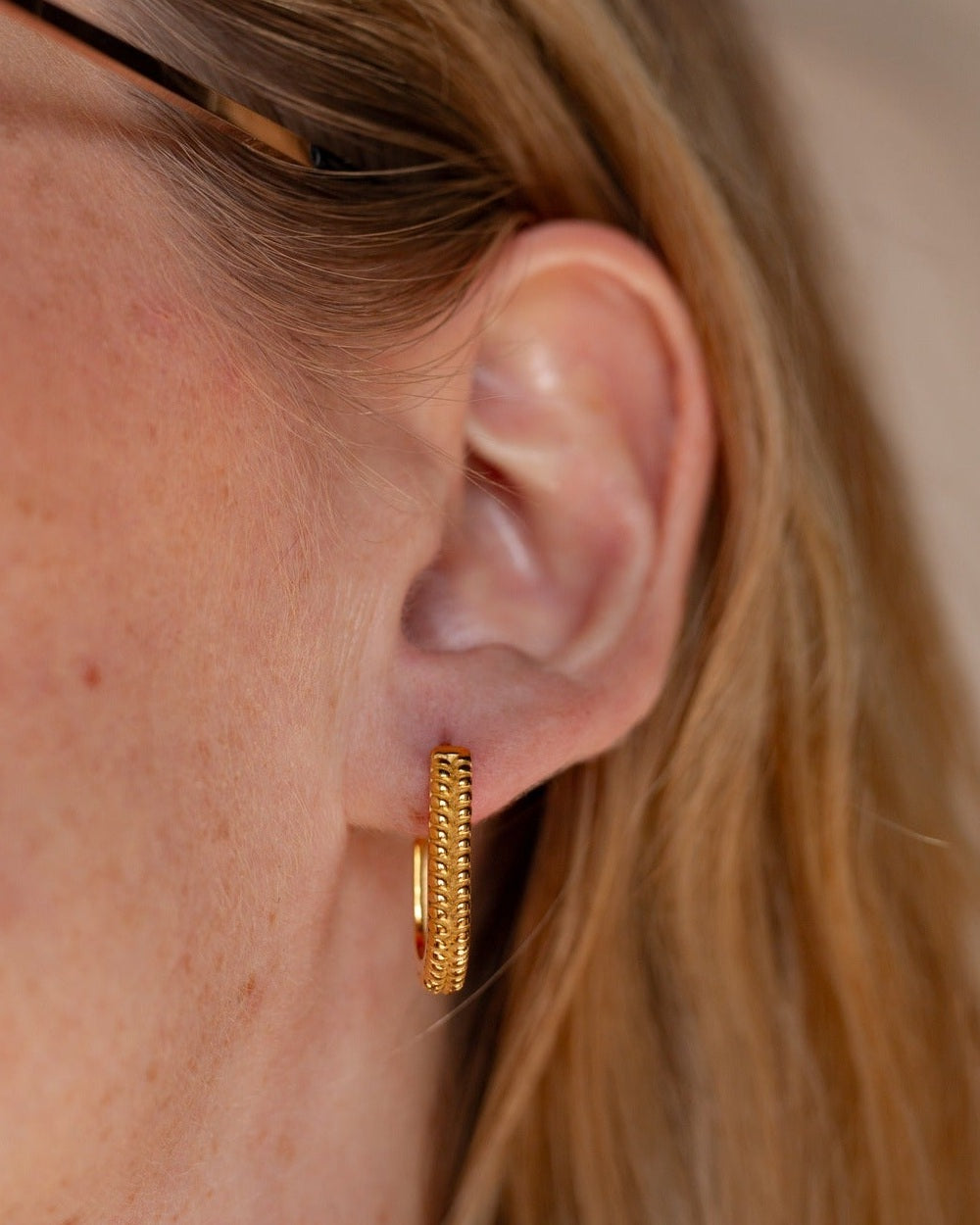 Electra textured rectangular gold hoop worn in a tight ear detail.
