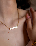 Fuck Bar Necklace shown in a close styled neckline view.