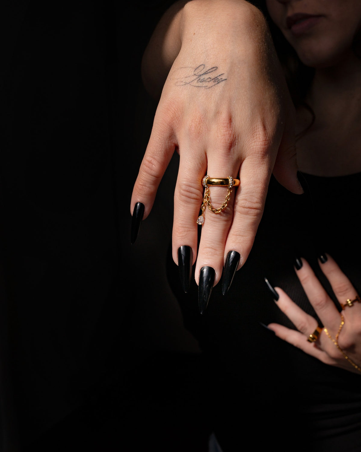 Gina gold statement ring shown against a black background in a close hand portrait.