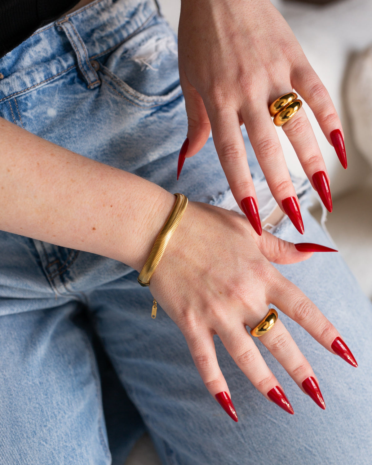 Isadora bracelet styled with gold rings and red nails