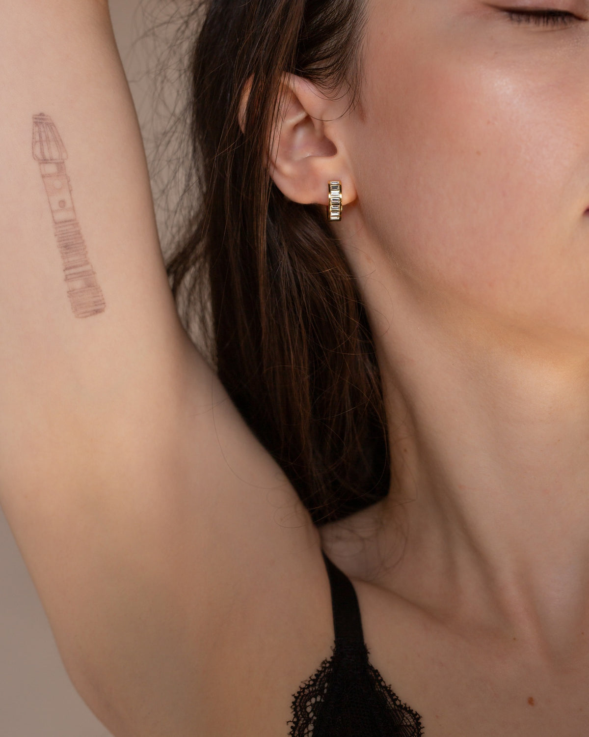 Josephine baguette stone gold huggie worn in a close-up portrait.