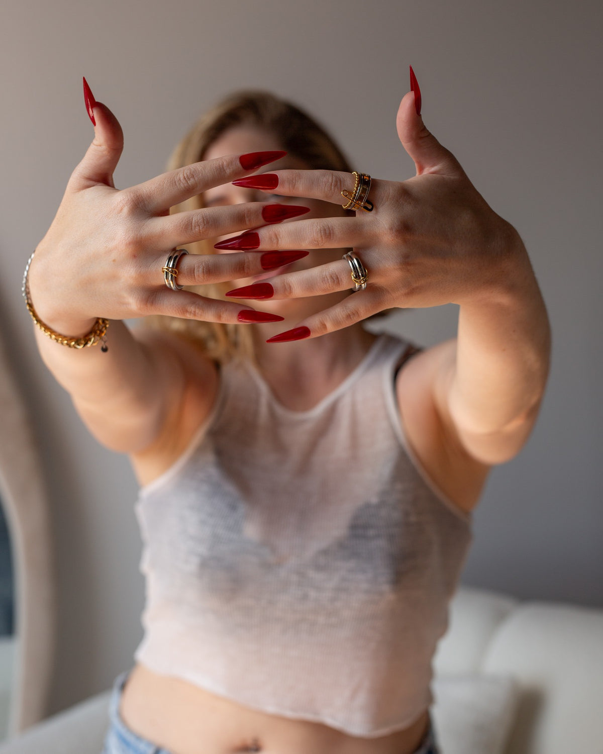Lin mixed-metal statement ring worn with red nails in an extended-hands portrait.