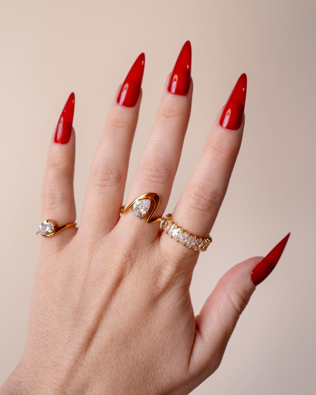 Liza clear-stone eternity band styled with layered gold rings on an upright hand with red nails.