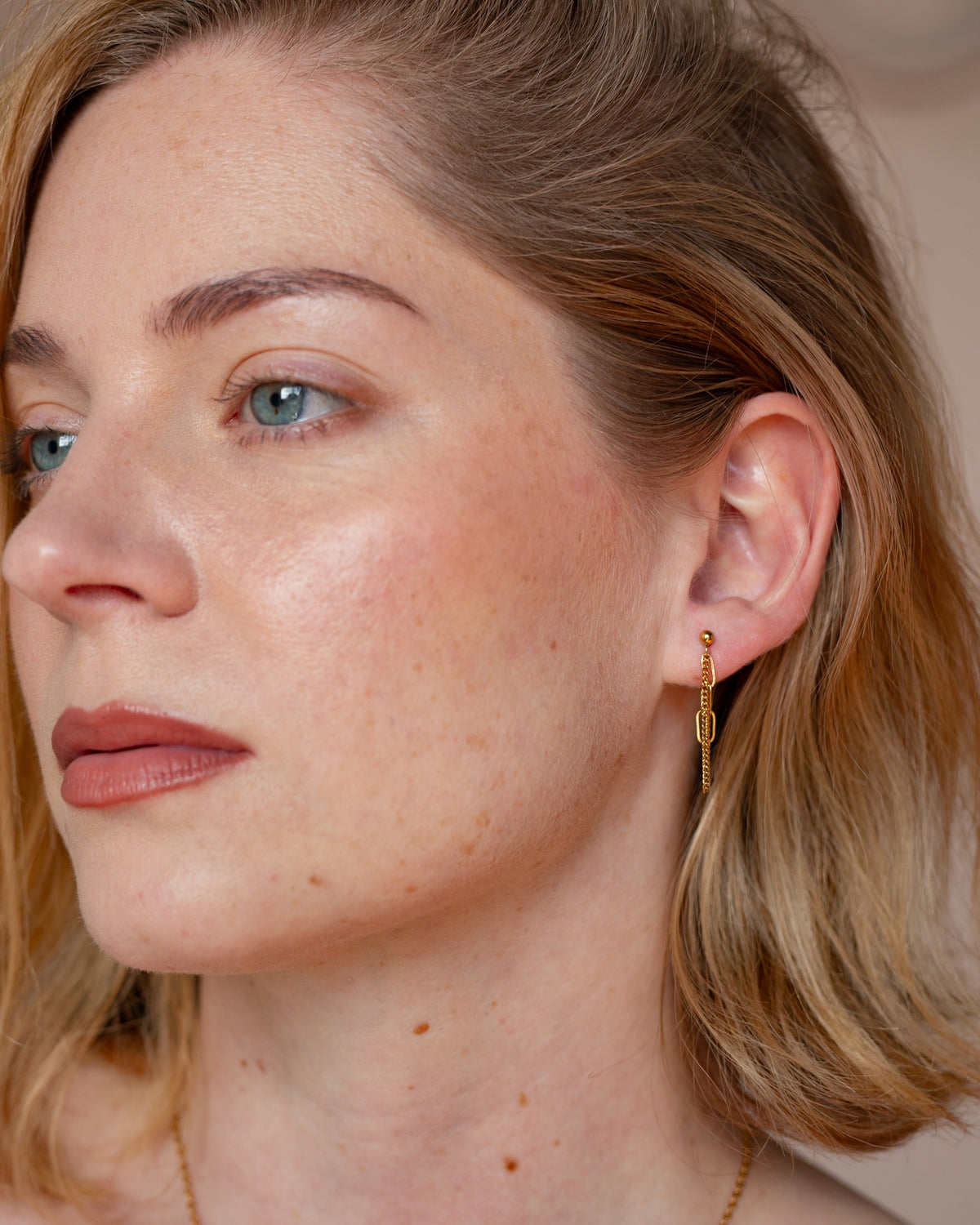 Melinoe gold layered chain earring worn in a polished close-up portrait.
