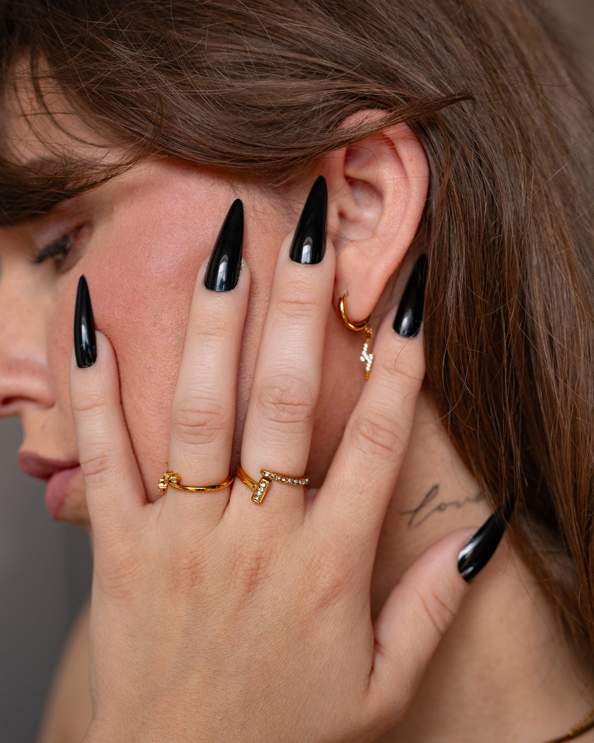 Noor gold bypass ring styled with delicate clear-stone rings and long black nails.