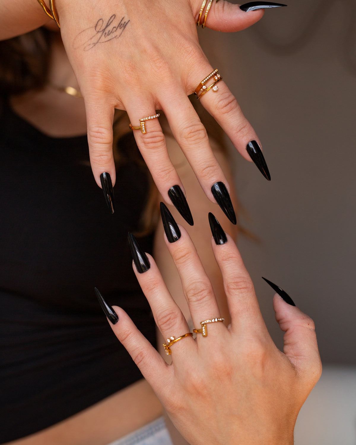 Noor sculptural clear-stone ring worn in a two-hand jewelry detail with black nails.