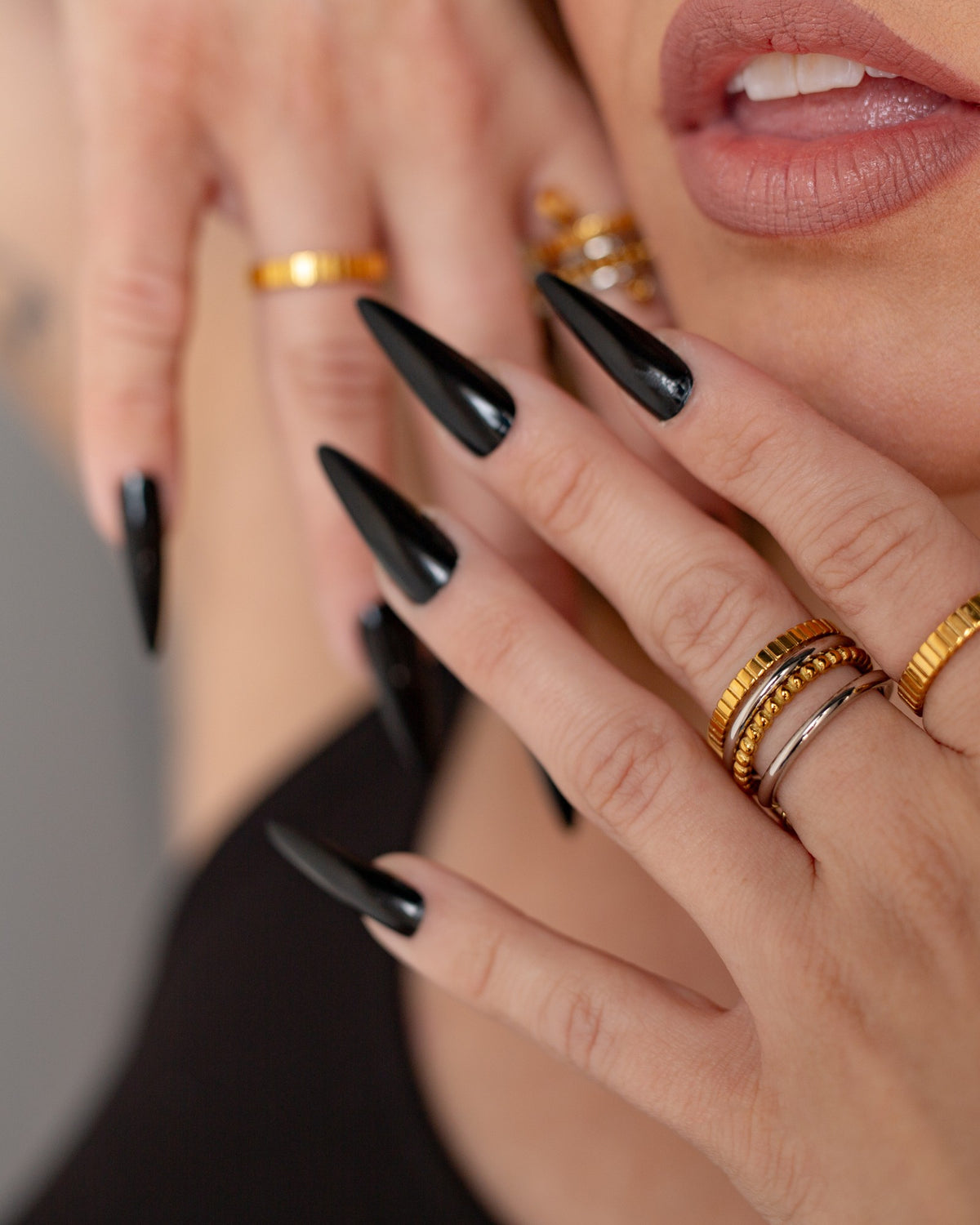 Prue stacked safety-pin ring worn with black nails in a layered jewelry portrait.