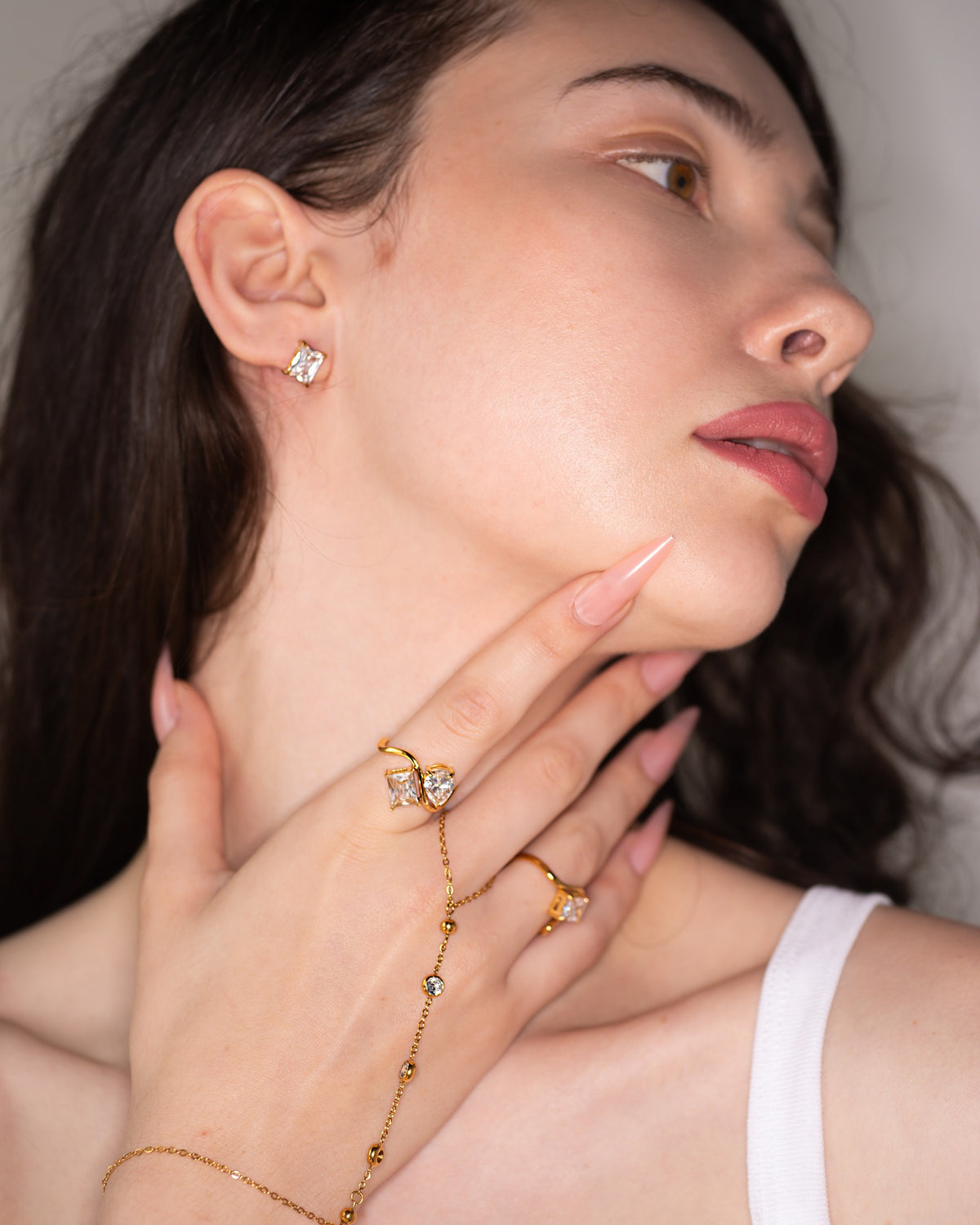 Talia pear-and-kite stone ring styled with a gold hand chain in a close face portrait.