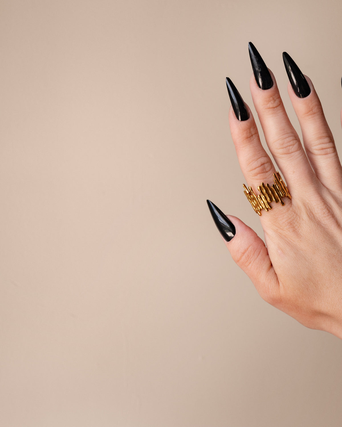 Vivi organic ridged gold ring displayed on an upright hand with long black nails.