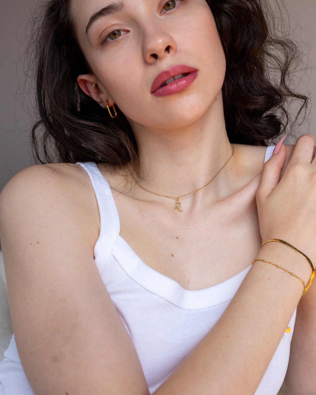 Gold zodiac necklace worn at the neckline, hover view.