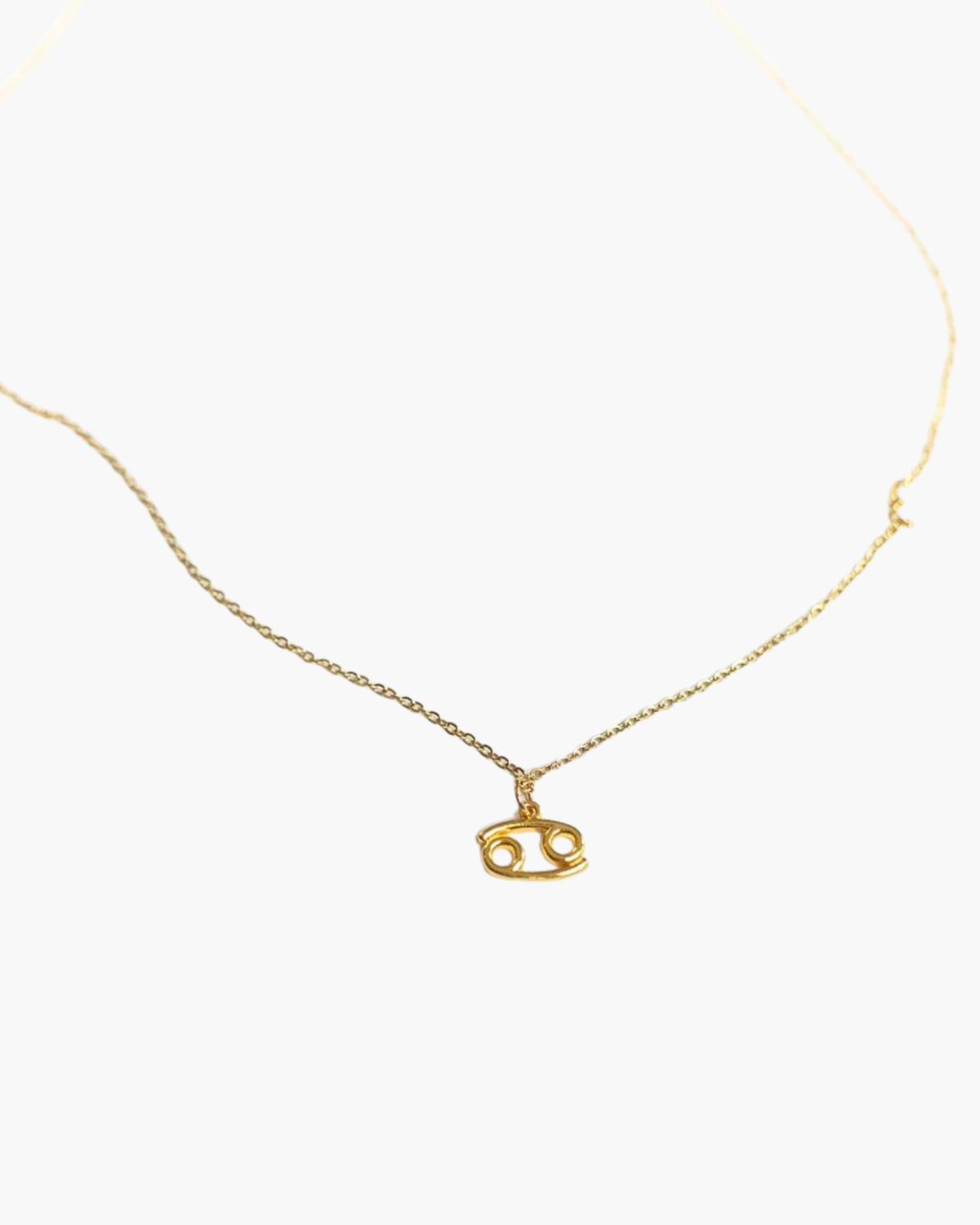 Gold-tone Cancer zodiac pendant necklace on a fine adjustable chain.